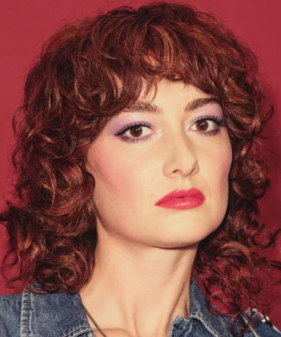 Model met een korte krullende coupe in een warme roodbruine haarkleur